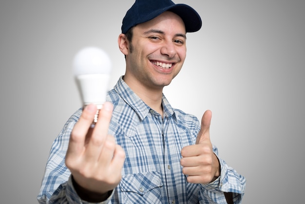 Retrato de un electricista sosteniendo una bombilla de ahorro de energía