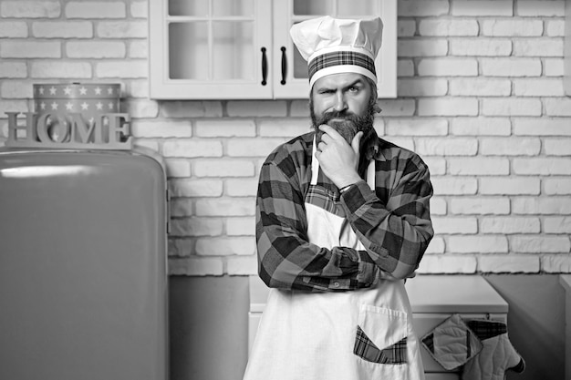 Retrato de un elegante cocinero barbudo en una cocina