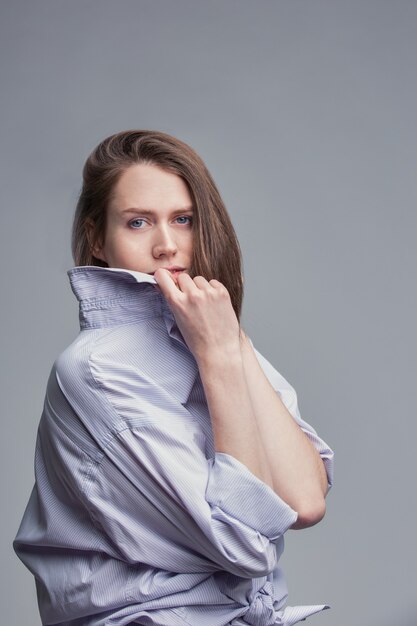 Retrato elegante de mulher jovem e bonita com olhos azuis sobre fundo cinza