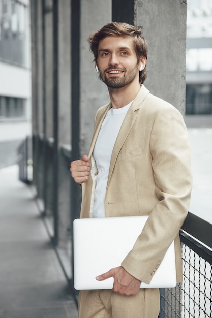 Retrato de elegante empresario barbudo llevar portátil al aire libre