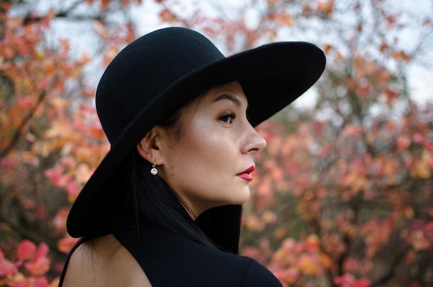 Retrato elegante hermosa mujer joven en un sombrero negro otoño