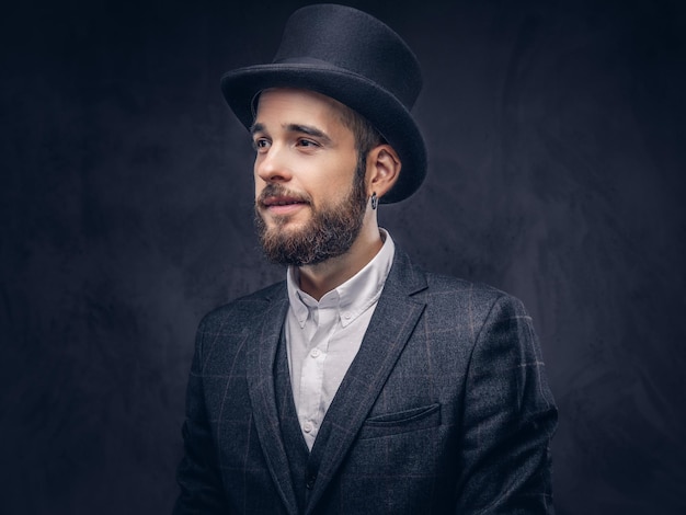 Retrato de un elegante hombre barbudo con un elegante traje y un sombrero cilíndrico, sobre un fondo oscuro.