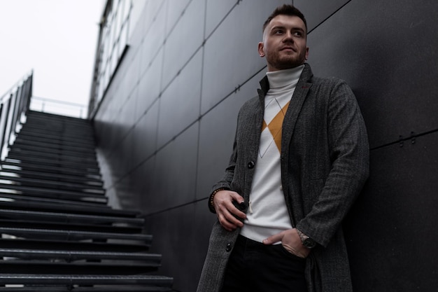 Retrato elegante de un hombre brutal en el fondo de un edificio gris moderno