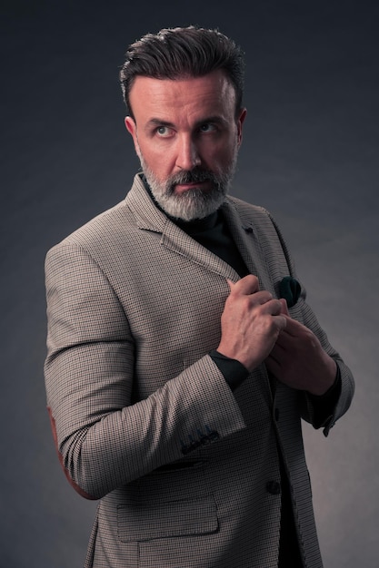 Retrato de un elegante hombre de negocios de alto nivel con barba y ropa informal de negocios en un estudio fotográfico aislado en un fondo oscuro gesticulando con las manos. foto de alta calidad