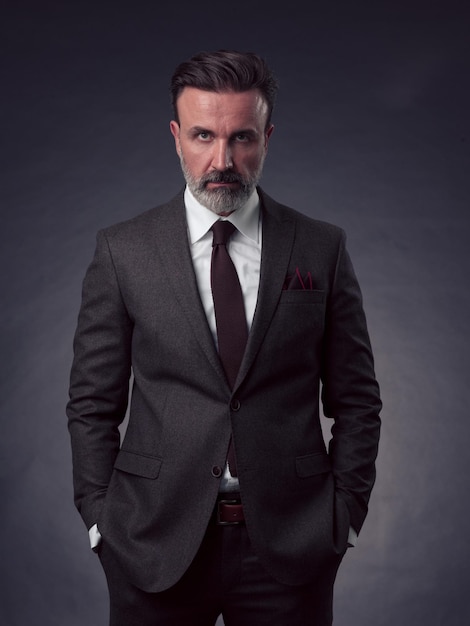 Retrato de un elegante hombre de negocios de alto nivel con barba y ropa informal de negocios en un estudio fotográfico aislado en un fondo oscuro gesticulando con las manos. foto de alta calidad