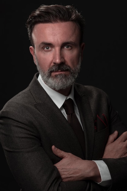 Retrato de un elegante hombre de negocios de alto nivel con barba y ropa informal de negocios en un estudio fotográfico aislado en un fondo oscuro gesticulando con las manos. foto de alta calidad