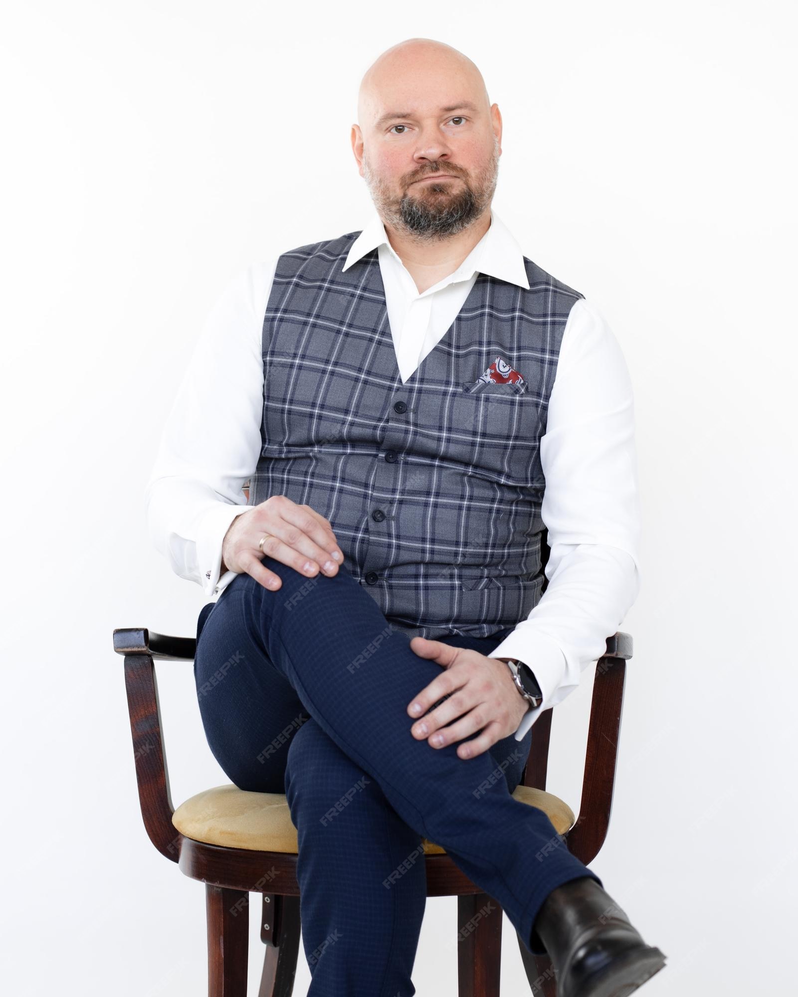 Retrato de un elegante hombre de negocios de mediana con chaleco gris, pantalones vaqueros camisa blanca sentado en silla con | Foto Premium