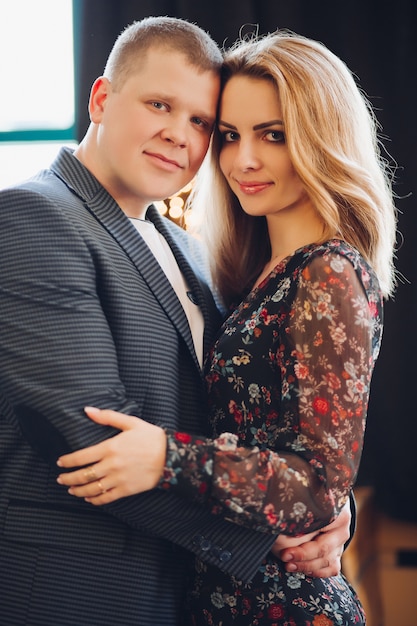 Retrato de elegante joven pareja feliz en el amor, sonriendo y abrazando