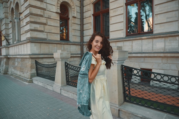 Retrato de elegante mujer morena sonriente, feliz caminando por la calle