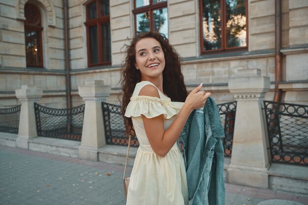 Retrato de elegante mujer morena sonriente, feliz caminando por la calle