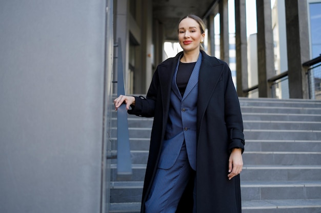 Retrato de una elegante mujer de negocios aferrándose a los pasamanos de las escaleras de un edificio moderno