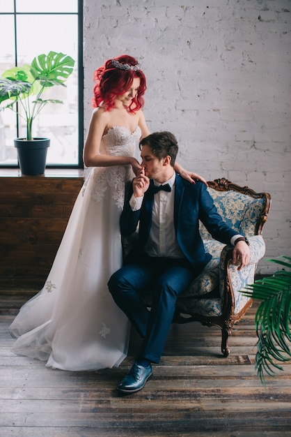 Retrato de elegantes recién casados sentados en una silla vintage