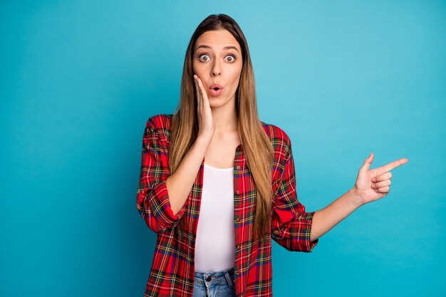 Retrato de ella, bonita, atractiva, encantadora, bastante asombrada, aturdida, chica de pelo largo con camisa a cuadros, demostrando una solución de decisión aislada sobre un fondo de color azul vibrante de brillo vivo brillante