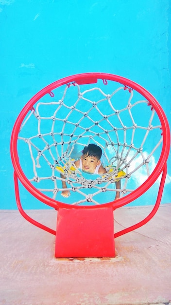 Foto retrato em alto ângulo de um menino visto através de um aro de basquete enquanto nada na piscina