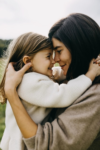 Foto retrato em close-up de mãe e filha brincando de nariz a nariz sorrindo