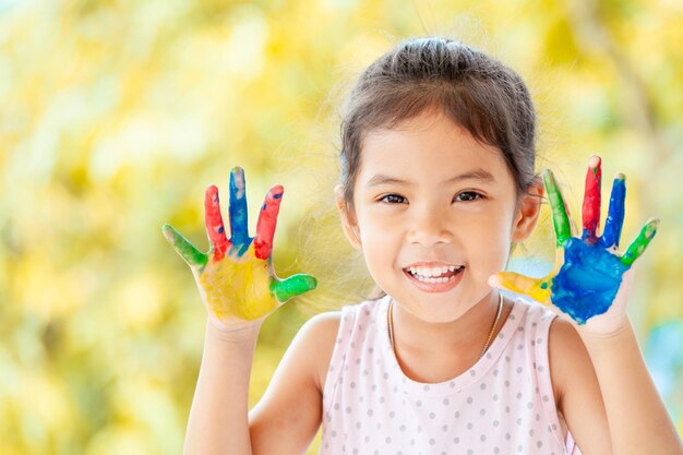 Foto retrato em close-up de menina sorridente com mãos pintadas