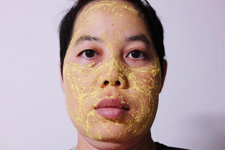 Foto retrato em close-up de mulher aplicando máscara facial contra a parede