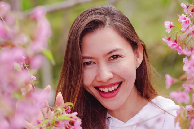 Retrato em close-up de mulher sorridente por planta em flor