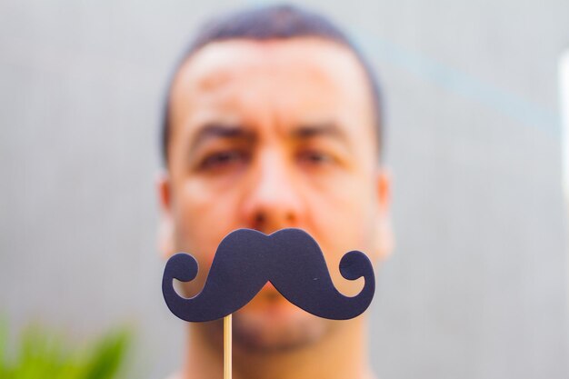 Foto retrato em close-up de um homem adulto segurando um suporte de bigode