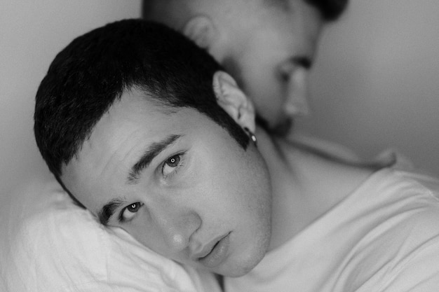 Retrato em close-up de um homem gay abraçando seu namorado contra a parede