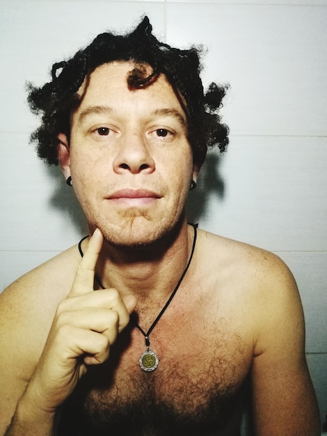 Foto retrato em close-up de um homem sem camisa sentado contra a parede