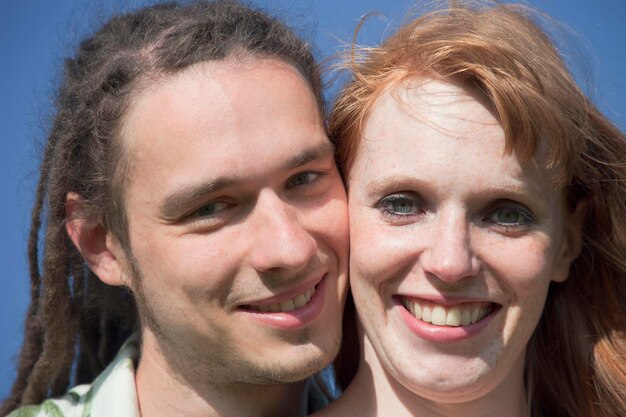 Retrato em close-up de um jovem casal sorridente contra um céu claro