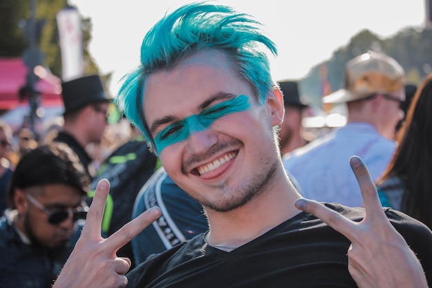 Retrato em close-up de um jovem com cabelo tingido mostrando um sinal de paz