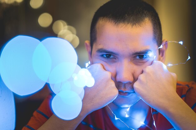 Foto retrato em close-up de um jovem com uma luz de corda iluminada