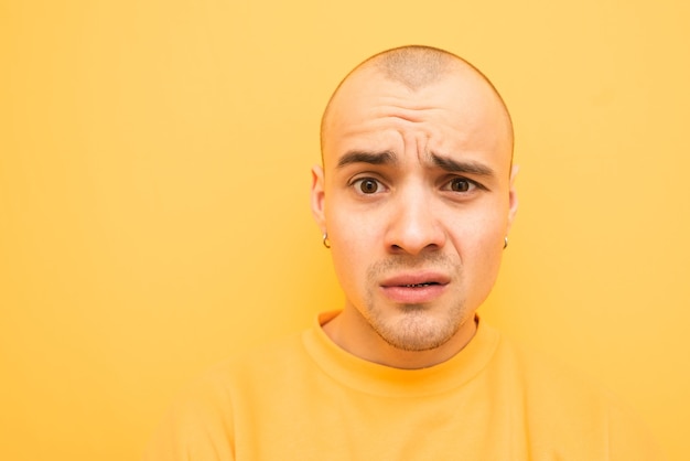 Retrato em close-up de um jovem surpreso em um fundo amarelo e vestindo roupas amarelas