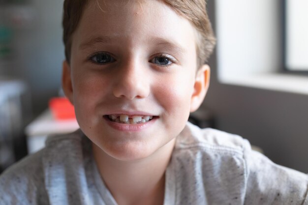 Retrato em close-up de um menino de escola primária sorridente sentado em uma mesa na sala de aula