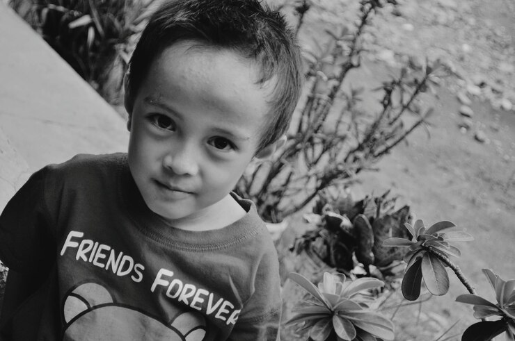 Foto retrato em close-up de um menino sentado junto a plantas