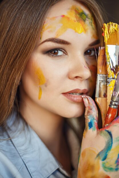 Foto retrato em close-up de uma artista segurando pincéis