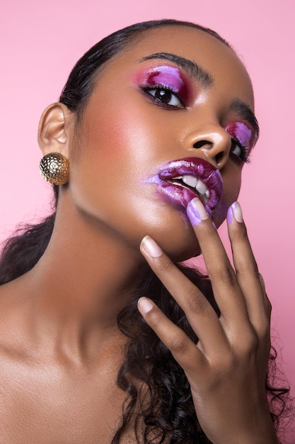 Foto retrato em close-up de uma bela jovem com maquiagem contra um fundo rosa