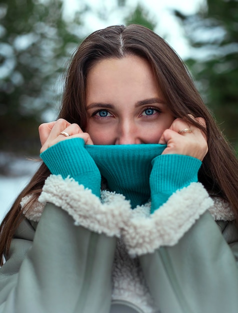 Retrato em close-up de uma bela jovem morena no parque de inverno