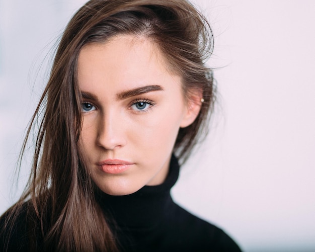 Retrato em close-up de uma bela mulher de pé contra um fundo branco