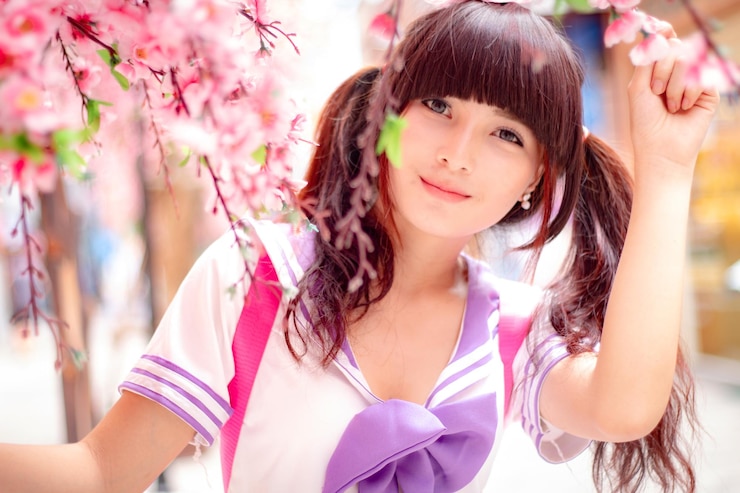 Foto retrato em close-up de uma estudante com flores de cerejeira cor-de-rosa na cidade