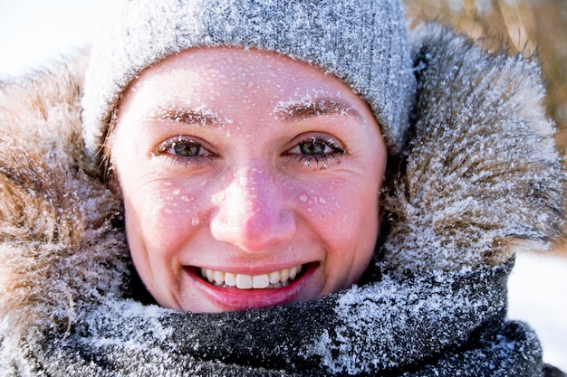 Foto retrato em close-up de uma jovem de roupas quentes com neve