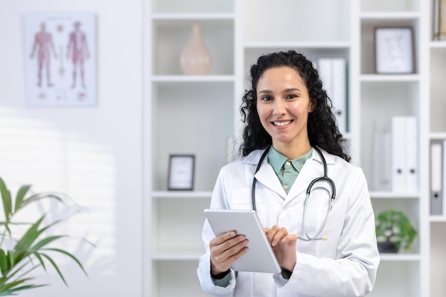 Retrato em close-up de uma jovem médica latino-americana de pé no escritório em um casaco branco