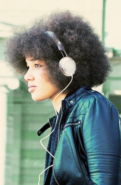 Retrato em close-up de uma jovem ouvindo música através de fones de ouvido