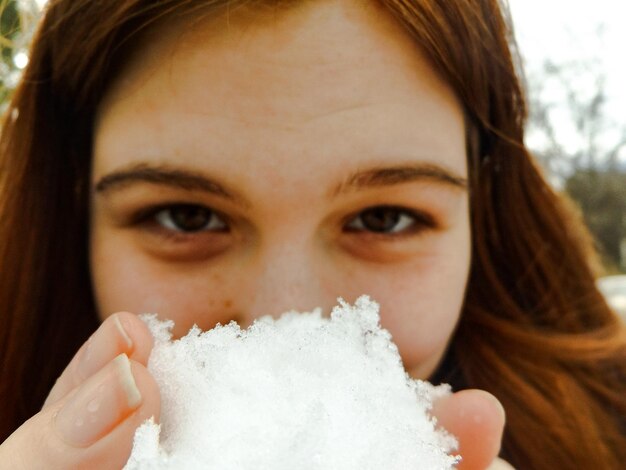 Foto retrato em close-up de uma jovem segurando a neve