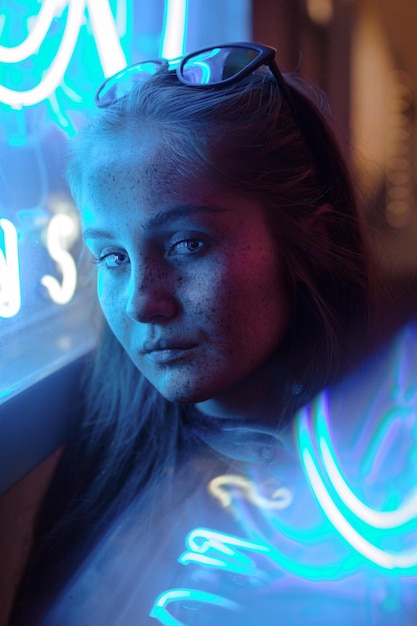 Retrato em close-up de uma jovem sentada junto a uma janela iluminada