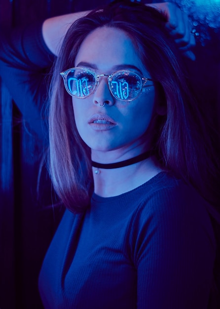 Retrato em close-up de uma jovem usando óculos de sol na sala escura