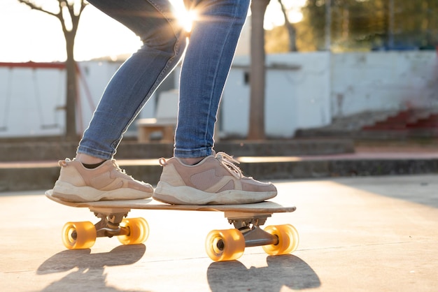 Retrato em close-up impessoal de um cruzeiro de skate de madeira e rosa com uma menina de sapatos de treino nele