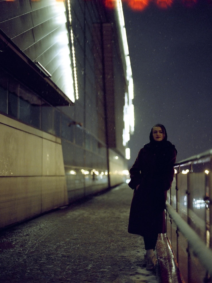 Foto retrato em comprimento completo de uma mulher de pé junto ao corrimão à noite