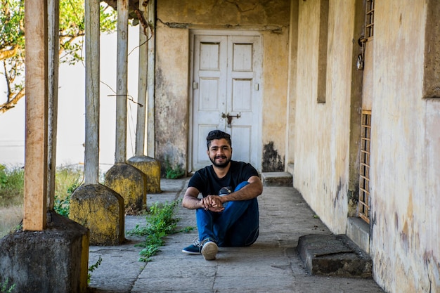 Retrato em comprimento de um jovem sentado no corredor