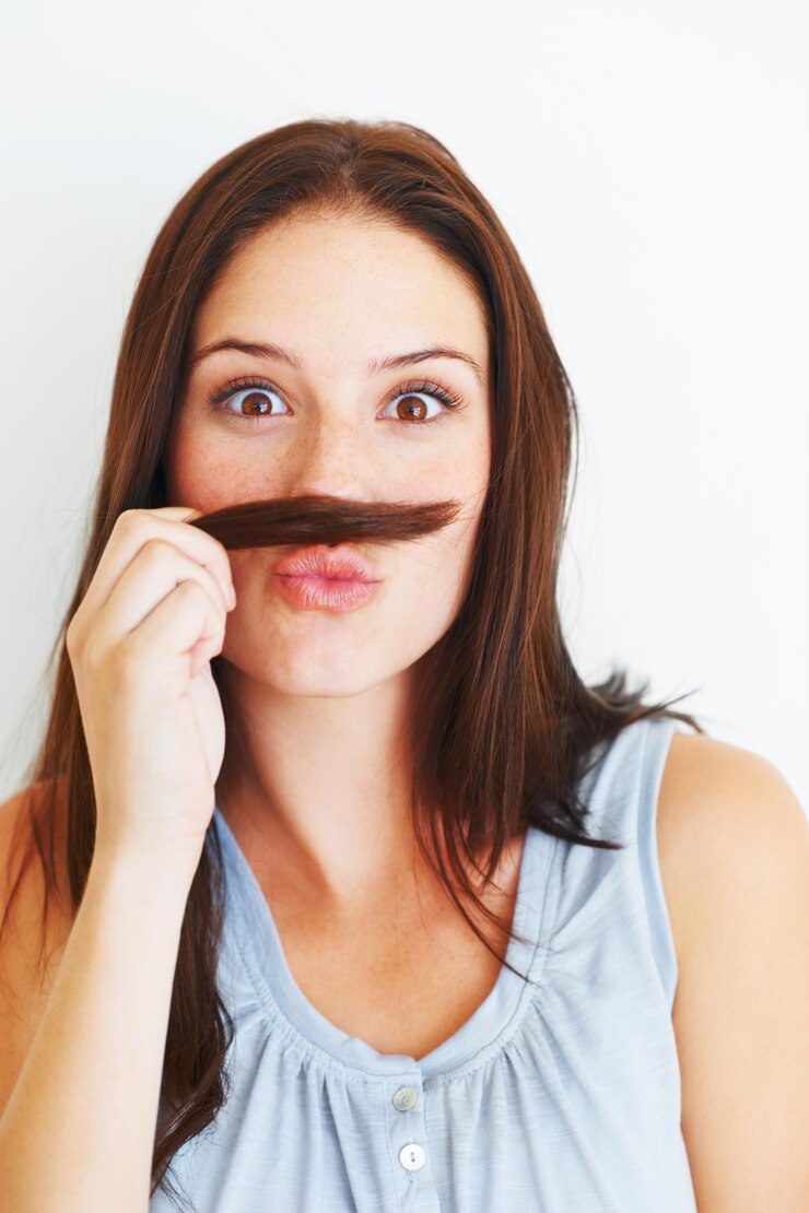 Foto retrato em quadrinhos e uma mulher com bigode de cabelo isolado em um fundo branco no estúdio sorriso engraçado e uma jovem sendo louca fazendo careta e brincando com penteado para comédia em um pano de fundo