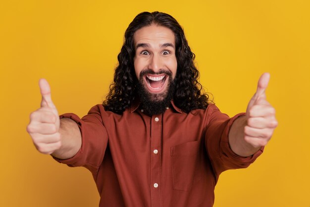 Retrato de emocionado chico positivo funky levantar la mano mostrar el pulgar hacia arriba signo sobre fondo amarillo