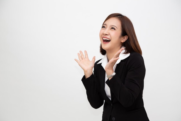 Retrato de emocionados gritando joven empresaria asiática de pie en traje formal de negocios aislado en blanco