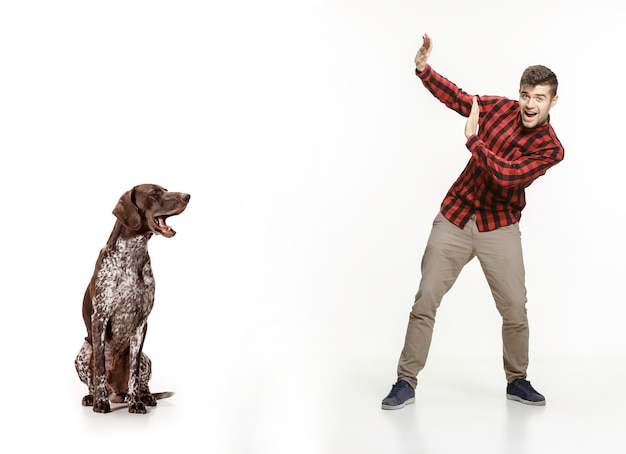 Retrato emocional do homem e seu cachorro, conceito de amizade e cuidado do homem e dos animais. ponteiro de pêlo curto alemão - cachorrinho kurzhaar isolado no fundo branco do estúdio