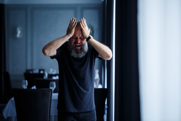 Retrato emocional de un hombre adulto canoso con barba en una camiseta negra